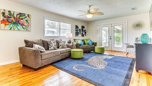 A living room with a sectional sofa, ottomans, a leopard print rug, and a ceiling fan. - Pensacola Home w/ Covered Patio: 1 Mi to Downtown! (Pensacola)