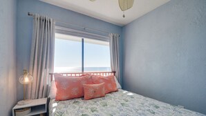 A bedroom with a bed, curtains, a nightstand, and a window with a view. - Coastal Condo w/ Balcony in North Myrtle Beach! (North Myrtle Beach)