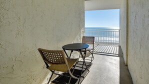 A balcony with a view of the ocean, two wicker chairs, and a small table. - Coastal Condo w/ Balcony in North Myrtle Beach! (North Myrtle Beach)