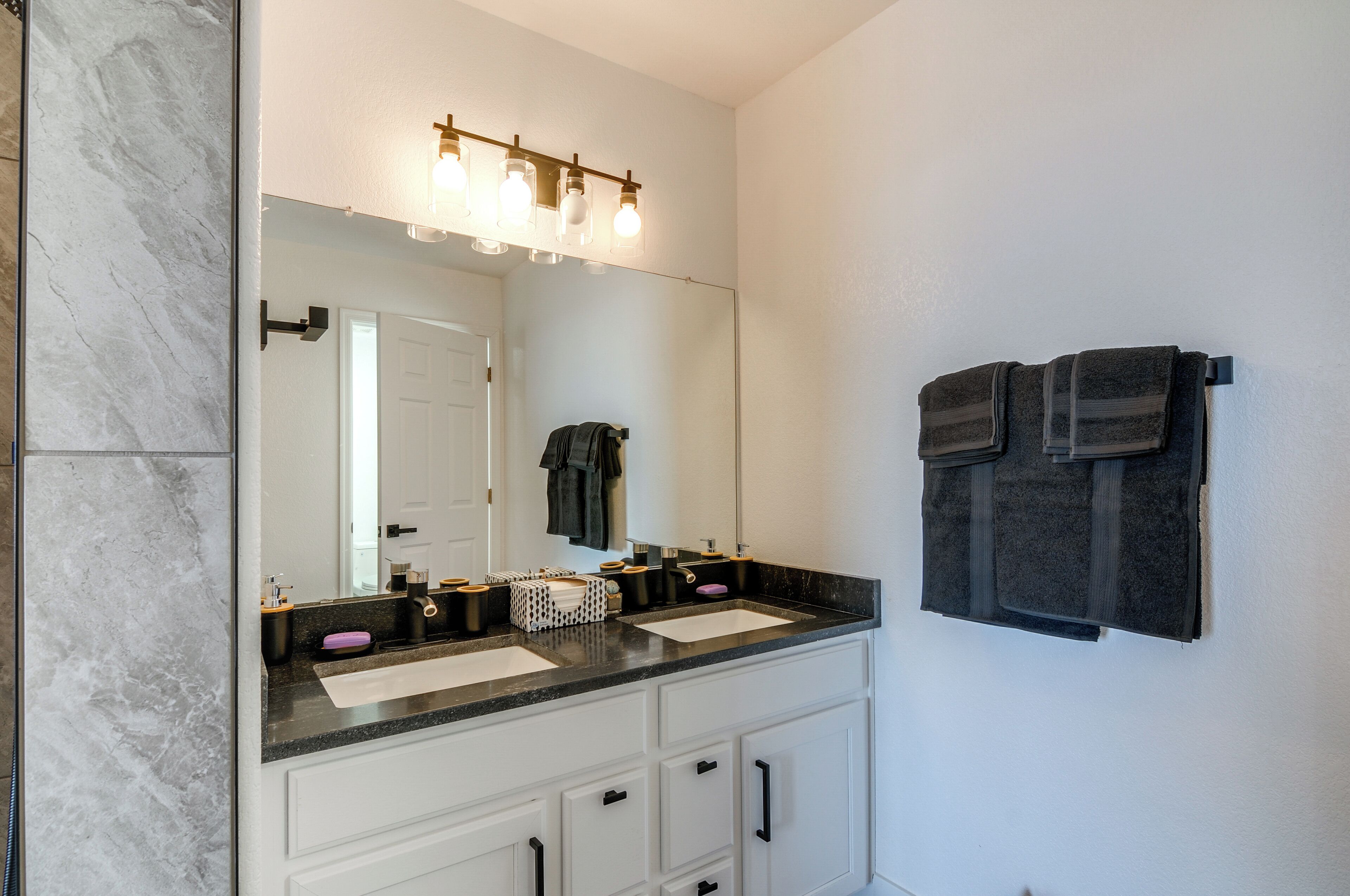 A bathroom with a double sink vanity, a large mirror, and a towel rack.
