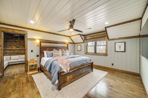 A bedroom with a wooden bed, a ceiling fan, and a large window. - Grand Broken Bow Cabin w/ Hot Tub & Spacious Deck! (Broken Bow)