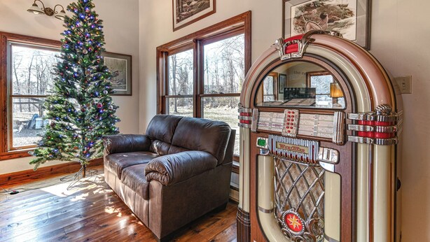 A room with a Christmas tree, a leather sofa, and a jukebox. - Cozy Mount Union Cabin w/ Fire Pit & River Access (Mount Union)