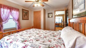 A bedroom with a bed, a ceiling fan, a window with curtains, and a door. - Cozy Mount Union Cabin w/ Fire Pit & River Access (Mount Union)