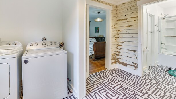 A laundry room with two white washing machines, a wooden door with peeling paint, and a patterned floor. - Danville Rental, Walk to Caesars Virginia Casino (Danville)