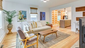 A modern living room with a sofa, coffee table, and a dining area with a kitchen in the background. - Danville Rental, Walk to Caesars Virginia Casino (Danville)