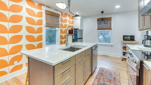 A modern kitchen with a central island, wooden cabinets, and a patterned backsplash. - Danville Rental, Walk to Caesars Virginia Casino (Danville)