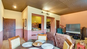 Un coin repas avec une table en bois dressée pour quatre personnes, un canapé marron et un téléviseur en arrière-plan.