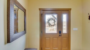 Une porte à deux battants en bois, ornée d’une guirlande, avec un banc et un miroir fixé au mur.
