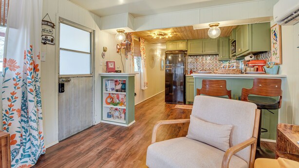 A compact kitchen with wooden cabinets, a refrigerator, and a dining area with a chair and table. - Pet-friendly Brownwood Home: Walk to Lake! (Brownwood)