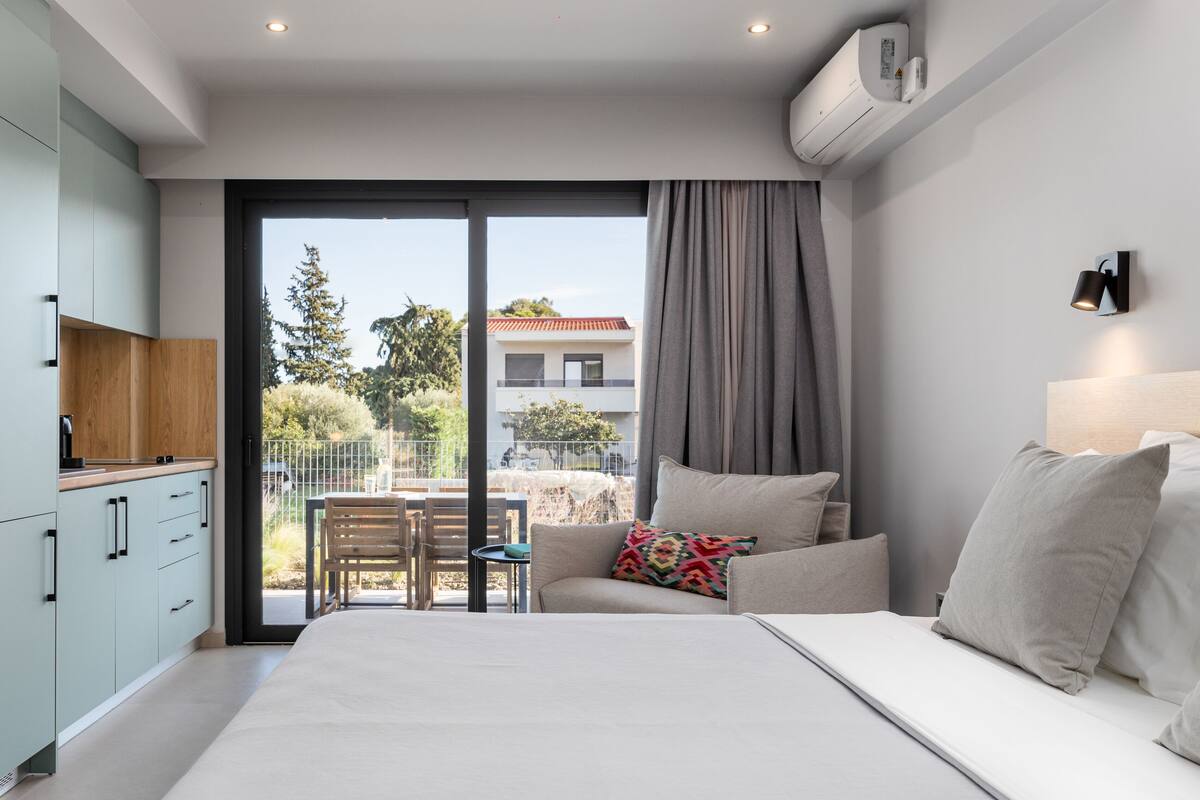 Ein modernes Schlafzimmer mit einem großen Bett, einer Couch und einem Essbereich mit Tisch und Stühlen.