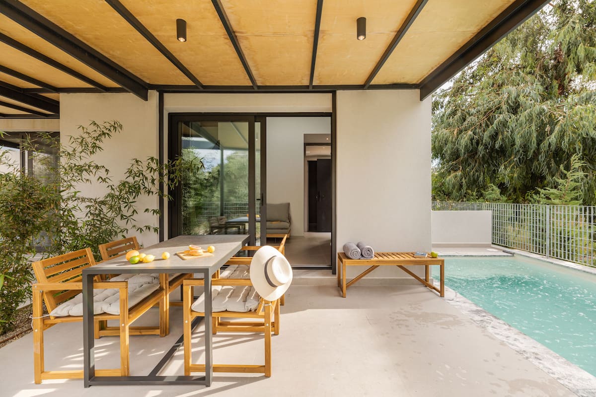 Ein Essbereich im Freien mit Tisch und Stühlen, ein Pool und eine überdachte Sitzgelegenheit.