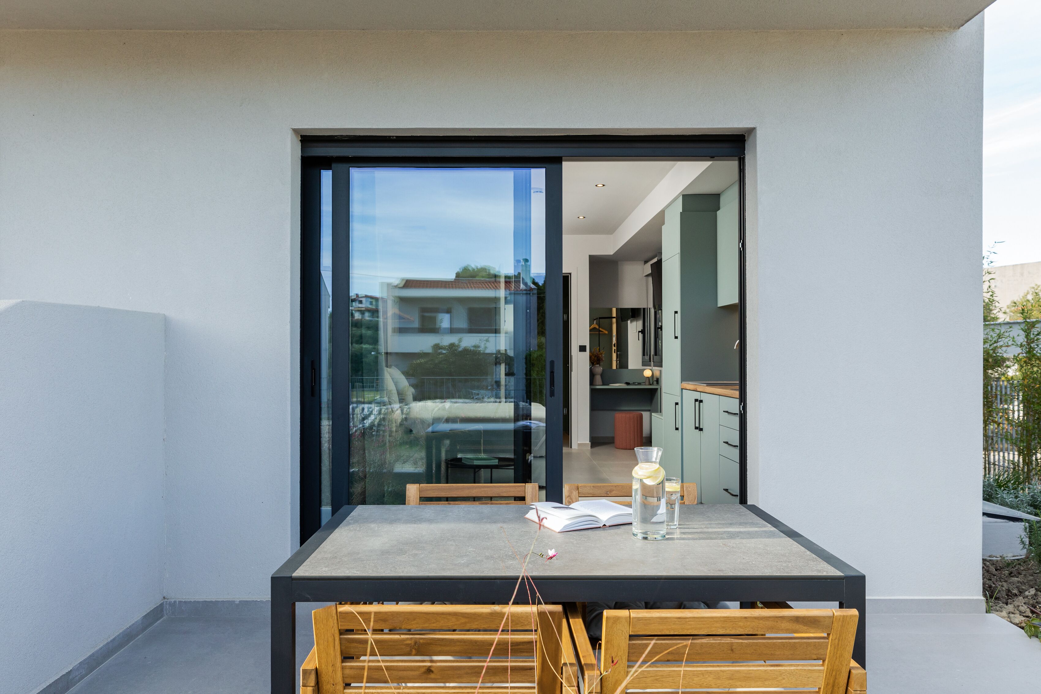 Un espace repas moderne avec une porte vitrée donnant sur une cuisine, comprenant une table avec des chaises et un livre.