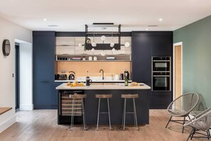 Una cocina moderna con una isla central, taburetes de bar y un horno empotrado.