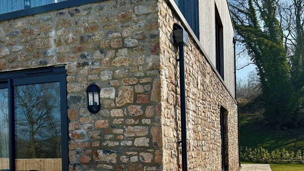 Un bâtiment moderne avec une façade en pierre et un jacuzzi à l’avant.