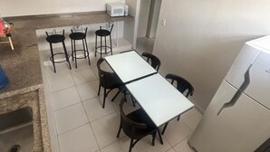 Ein Essbereich mit einem langen Tisch, vier Stühlen, einer Mikrowelle und einem Kühlschrank.