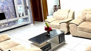 A modern living room with beige sofas, a black coffee table, and a marble-patterned wall. - Anastera Home Vila (Kigali)