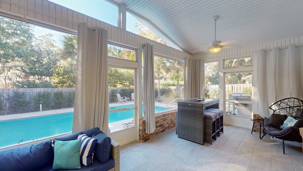 A sunlit patio with a pool, wicker furniture, and a barbecue area. - A Lifelong Dream - 3 bedroom, 2 bath with private swimming pool (Jekyll Island)
