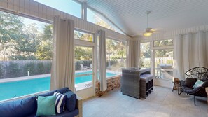 Une terrasse ensoleillée avec une piscine, des meubles en osier et un espace barbecue.