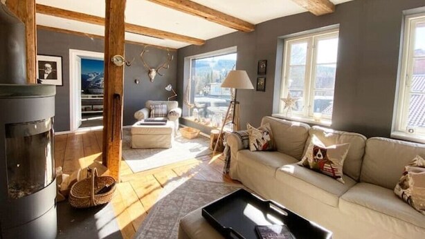 Ein gemütliches Wohnzimmer mit Kamin, einer Couch und einem großen Fenster.