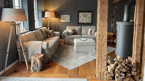 Ein gemütliches Wohnzimmer mit einer Couch, Sesseln, einem Couchtisch und einem Kamin.