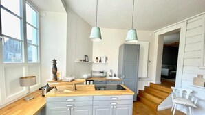 Moderni keittiö, jossa on keskeinen saareke, harmaat kaapit ja riippuvalaisimet.