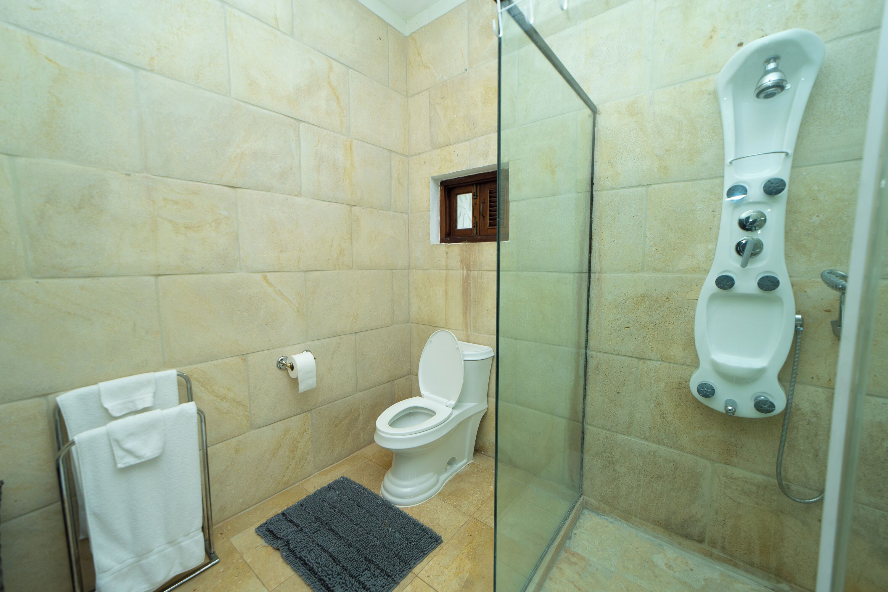 Un baño con inodoro, cabina de ducha de vidrio y perchero para toallas.