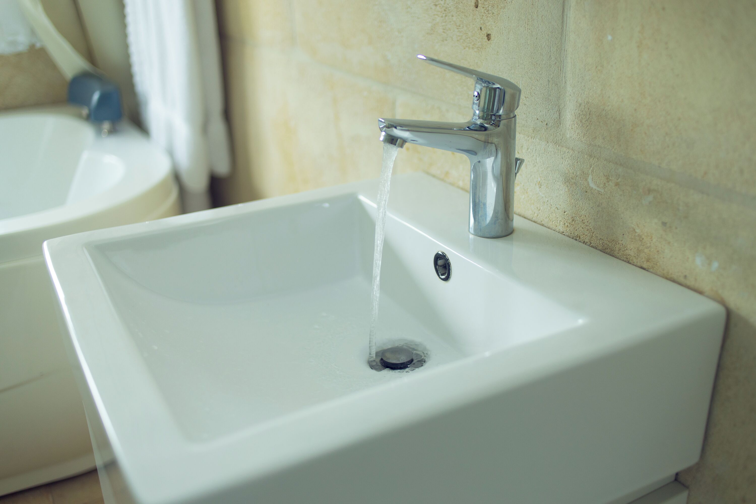A bathroom sink with a chrome faucet and running water.