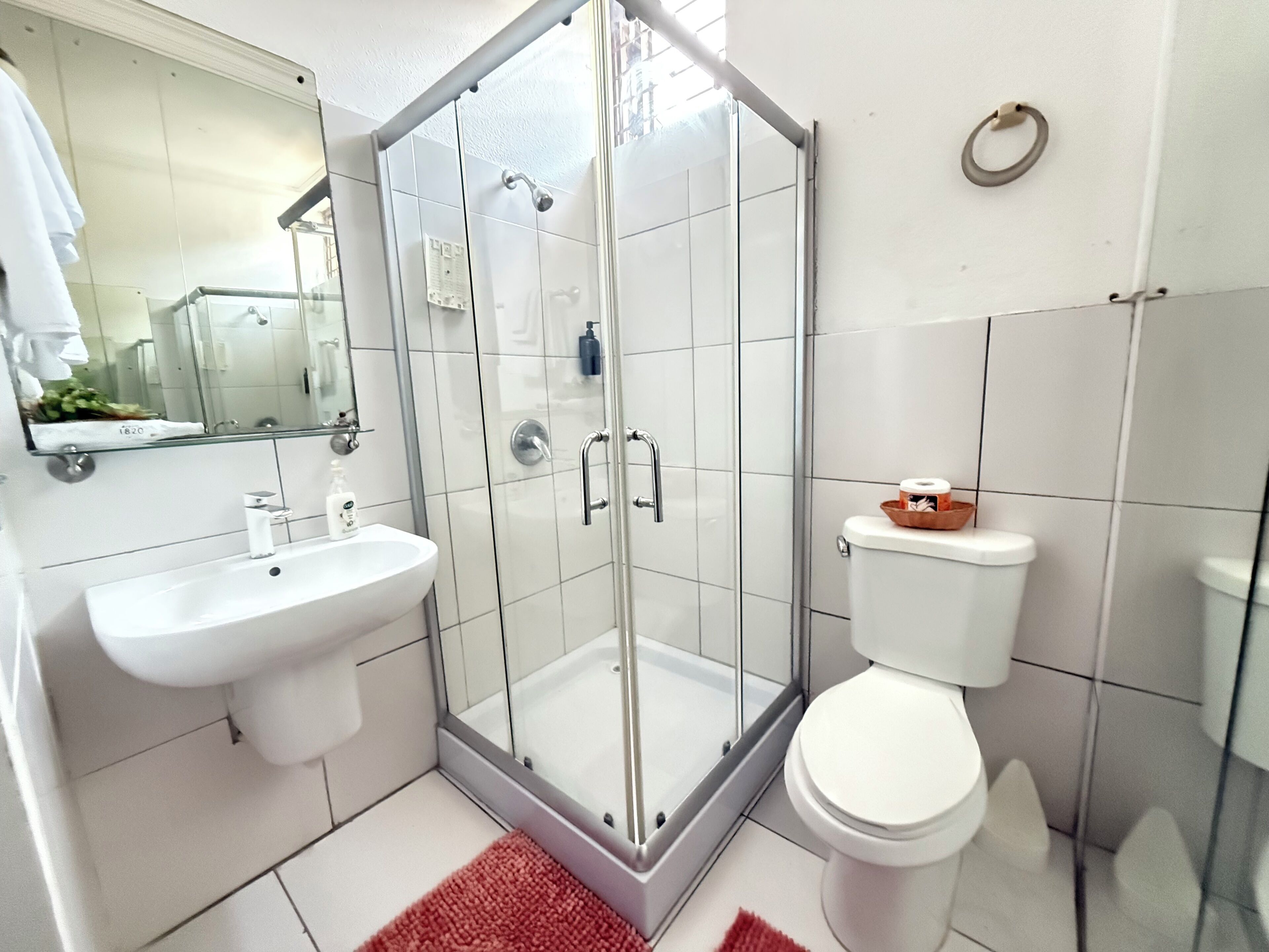 Ein modernes Badezimmer mit einer gläsernen Duschkabine, einem weißen Waschbecken und einer Toilette.