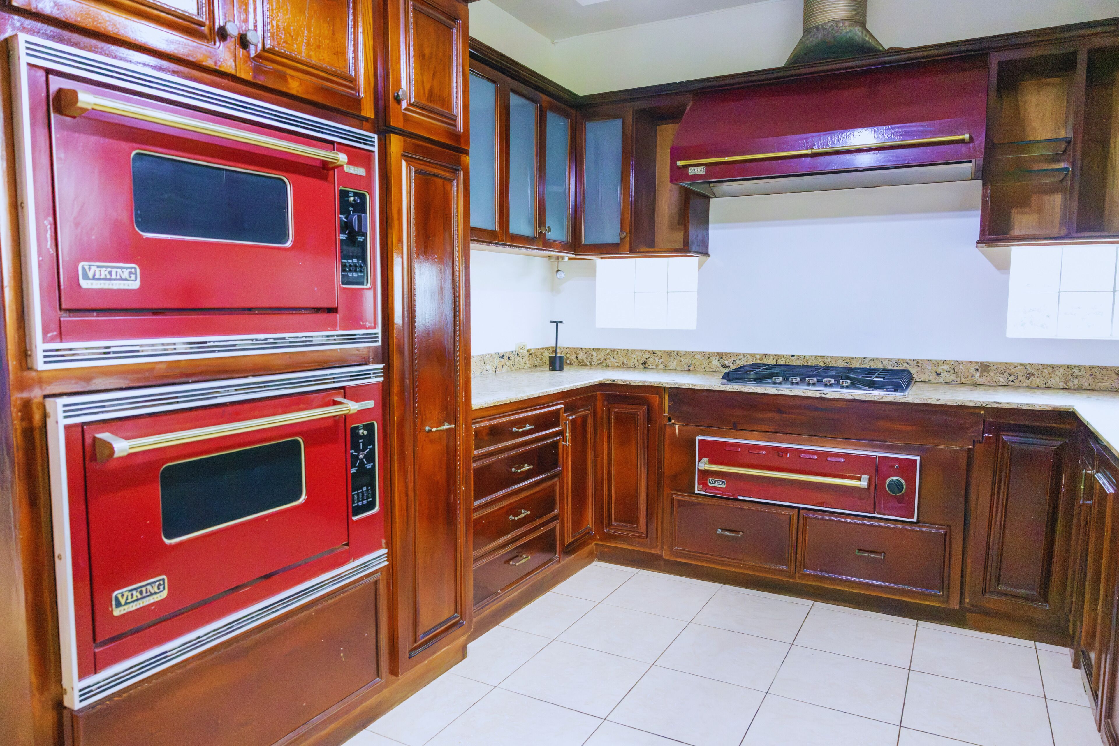 Una cocina con armarios de madera, un horno Viking rojo y una campana extractora de acero inoxidable.