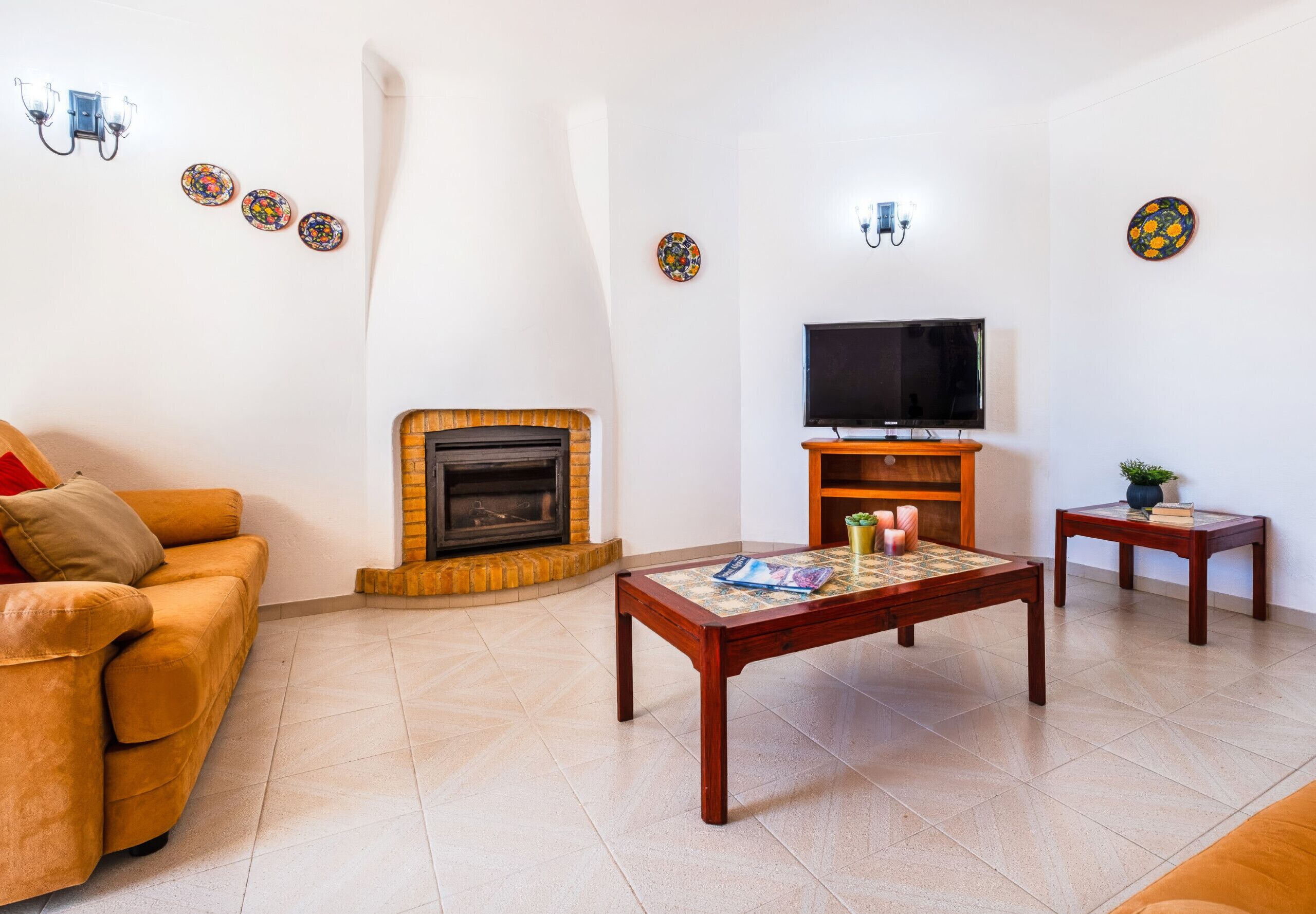 Una sala de estar con sofá, chimenea, televisor y mesa de centro.