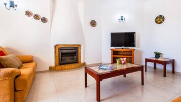 Una sala de estar con sofá, chimenea, televisor y mesa de centro.