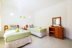 A room with two beds, a wooden dresser, and a mirror on the wall.