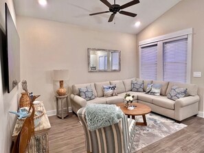 A living room with a sofa, a coffee table, a lamp, and a ceiling fan.
