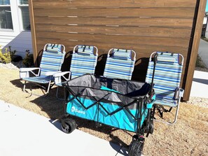Un entorno frente al mar con una fila de sillas de playa a rayas y un carro de playa azul y negro con la marca 'Sakey' a la vista.
