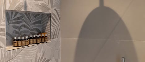 A shower area with a rain showerhead, a handheld showerhead, and a shelf with bottles.