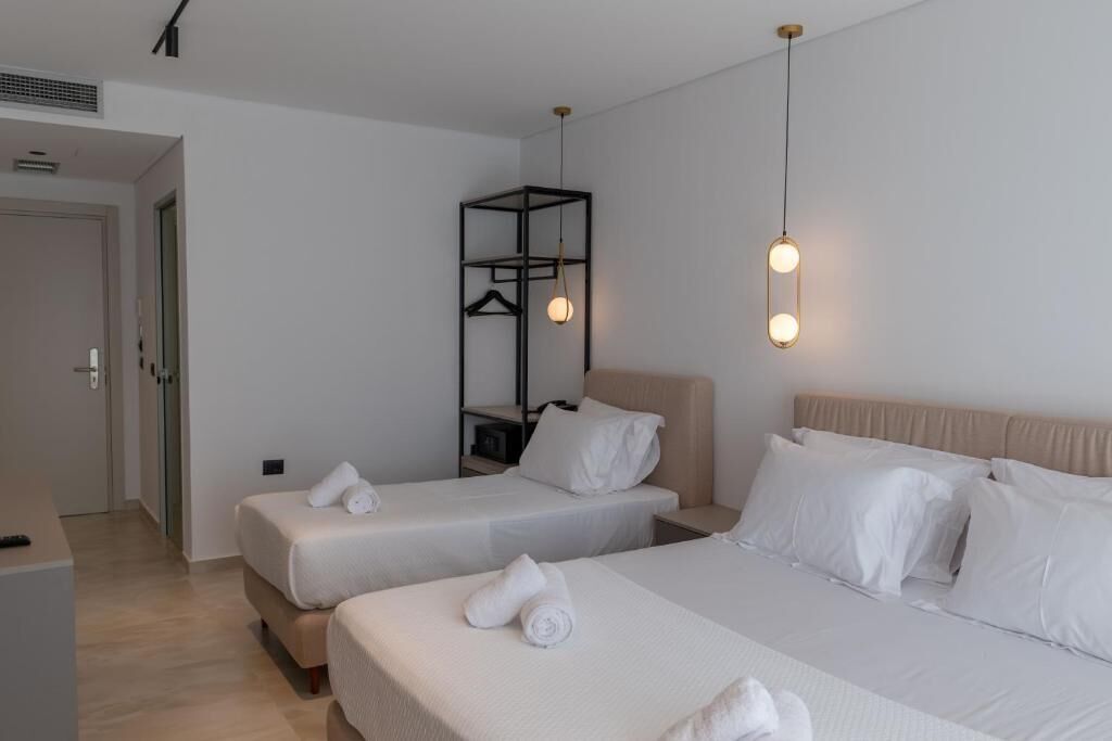 Une chambre d’hôtel avec deux lits, une armoire et un luminaire suspendu.