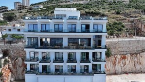 A multi-story building with balconies, large windows, and a rocky hillside background. - Litan Hotel (Sarandë)