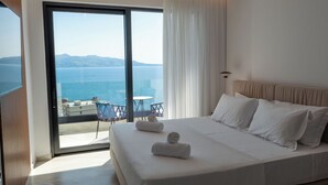 A hotel room with a large bed, a balcony with a table and chairs, and a view of the sea. - Litan Hotel (Sarandë)