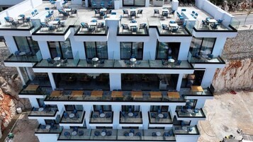 Un edificio de varios pisos con zonas de estar al aire libre en cada nivel, que incluyen mesas y sillas.