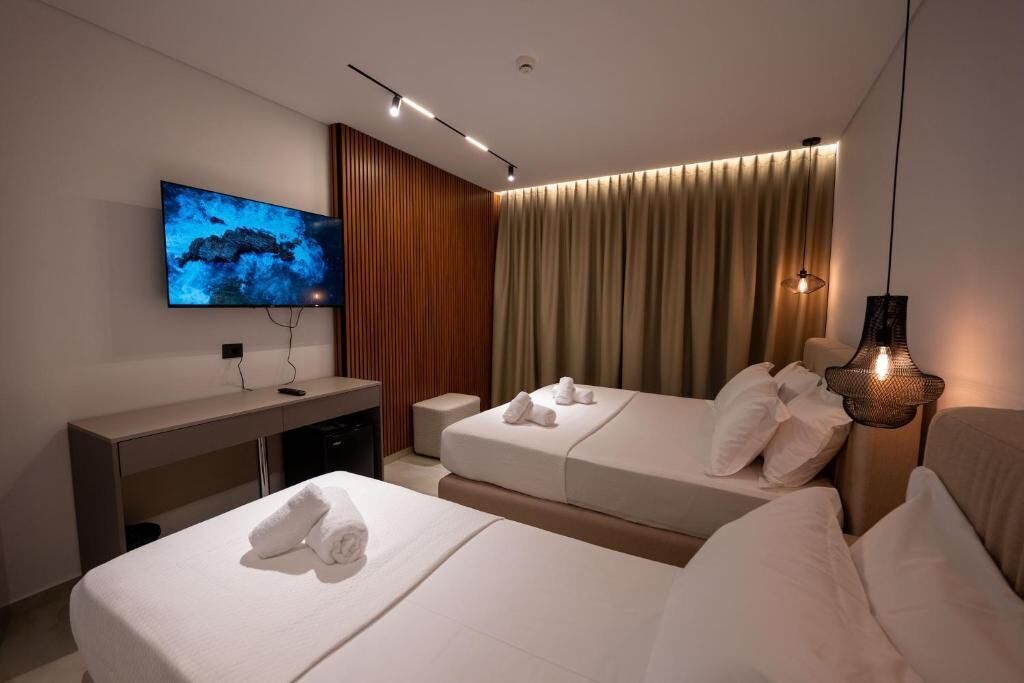 Una habitación de hotel con dos camas, un escritorio, un televisor y una cortina.