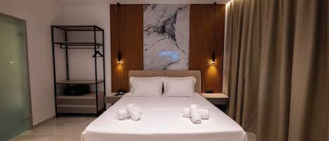 A modern hotel room with a large bed, a built-in shelf, and a marble wall.