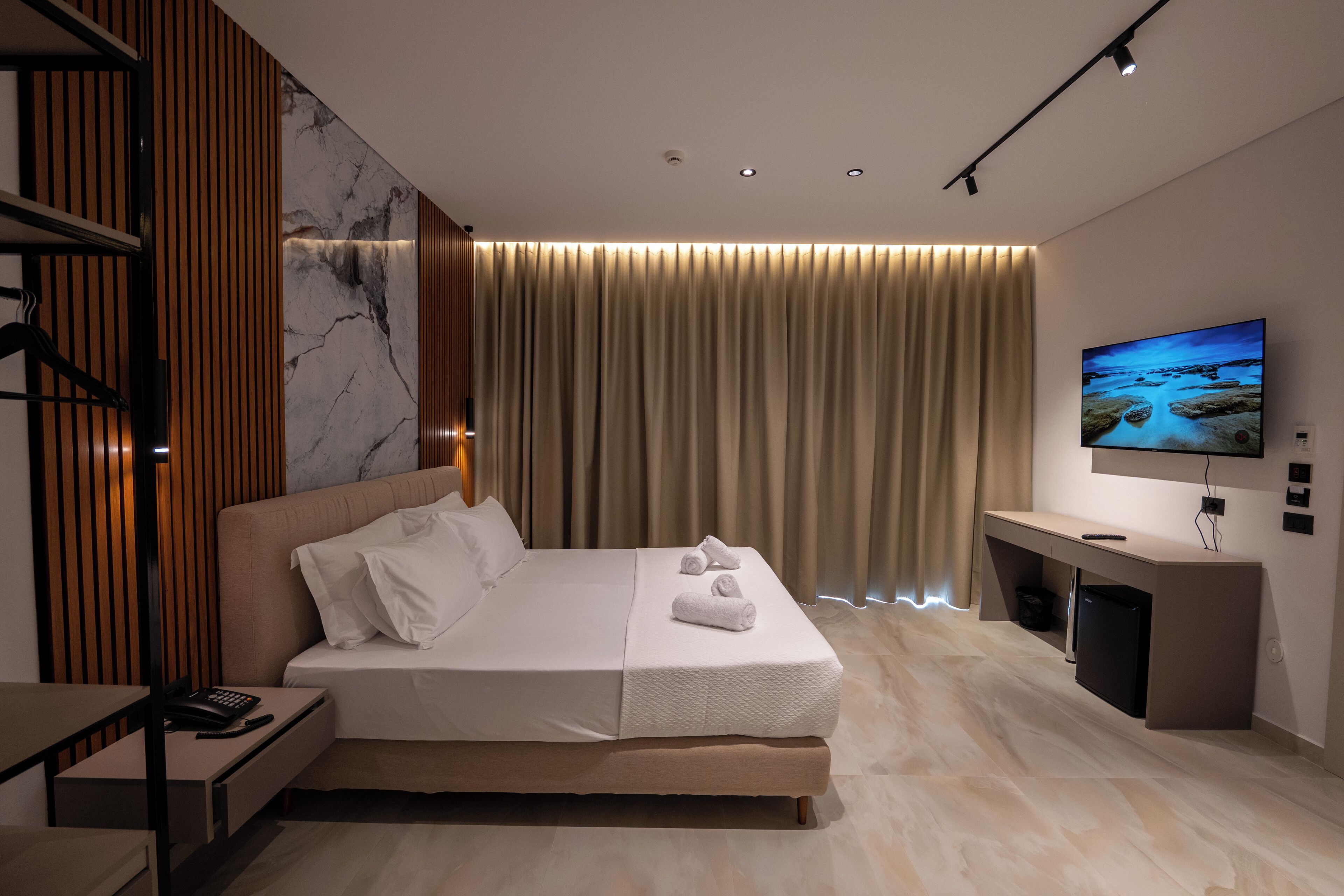 A modern hotel room with a large bed, a desk, and a TV.