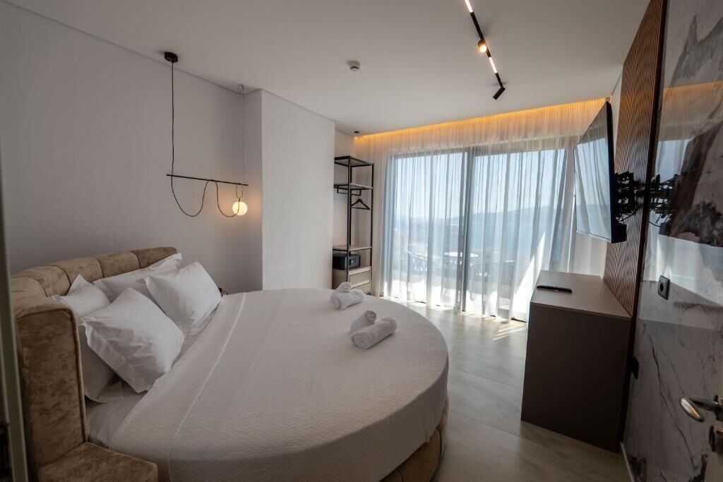 A modern hotel room with a large bed, a desk, and a view of the city.