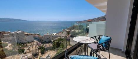 A balcony with a clear view of the sea and buildings.