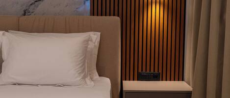 A modern bedroom with a marble headboard, a bedside table with a lamp, and a bench.