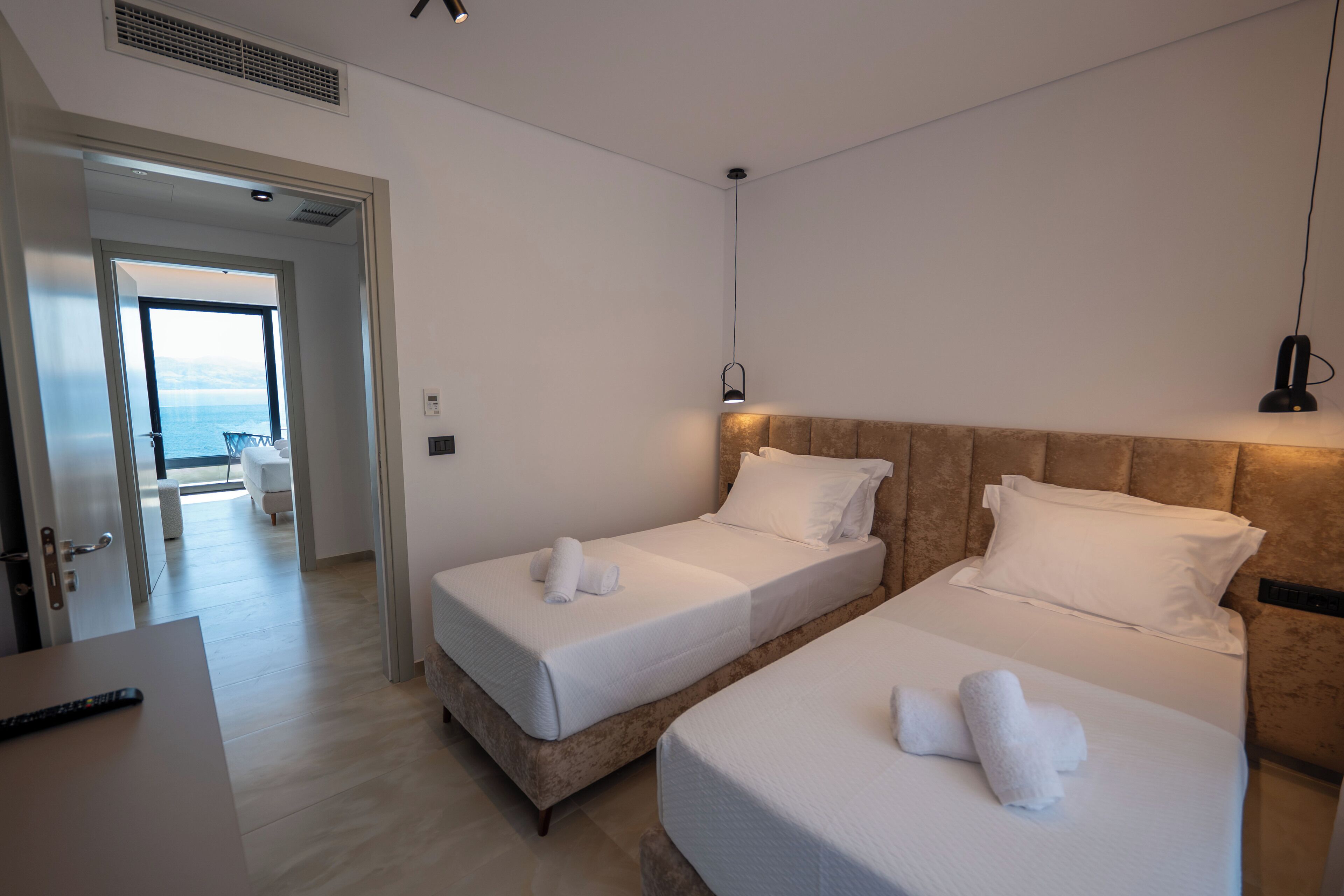 A hotel room with two beds, a view of the sea, and a modern design.