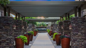 A covered walkway with stone walls and large planters along the sides. - Location, Luxury Amenities, Walk to everything! (Phoenix)