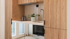 A modern kitchen with wooden cabinetry, a built-in oven, and a window overlooking the street.