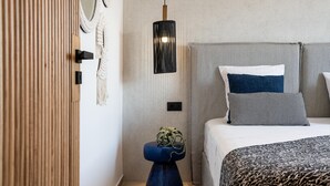 A bedroom with a bed, a bedside table with a plant, a wall-mounted light, and a striped curtain.