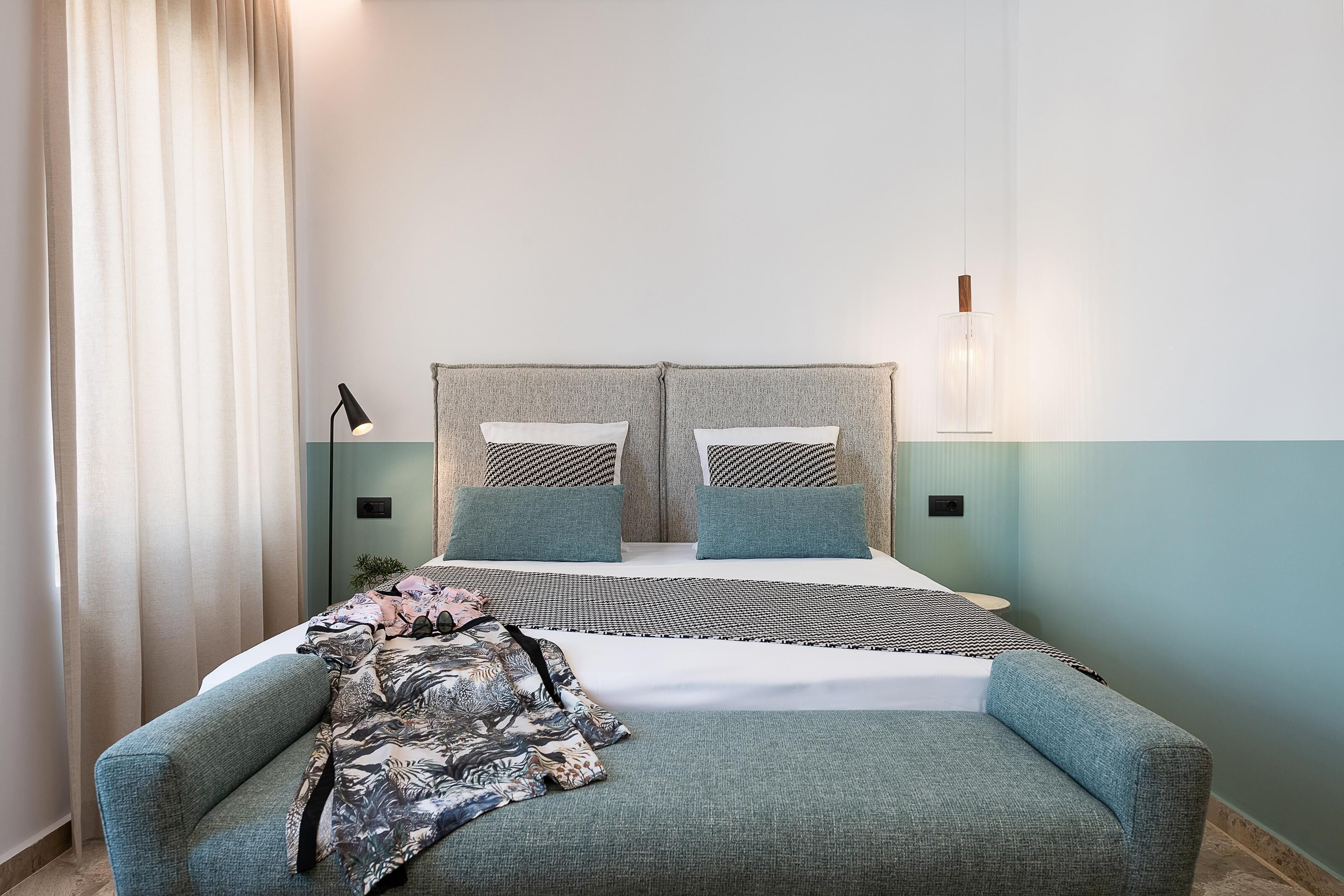 A neatly arranged bedroom with a bed, two bedside tables, a lamp, and a couch.